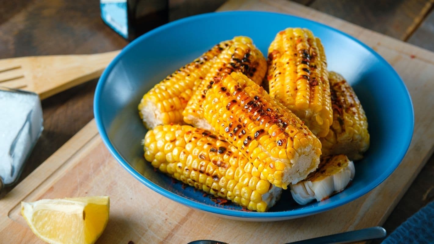Sabores de milho assado no grill em uma tigela azul, perfeito para churrasco ou acompanhamento. Com sabor defumado e crocante, ideal para lanches ou refeições saudáveis. Além de ser tipo nas festas de São João.