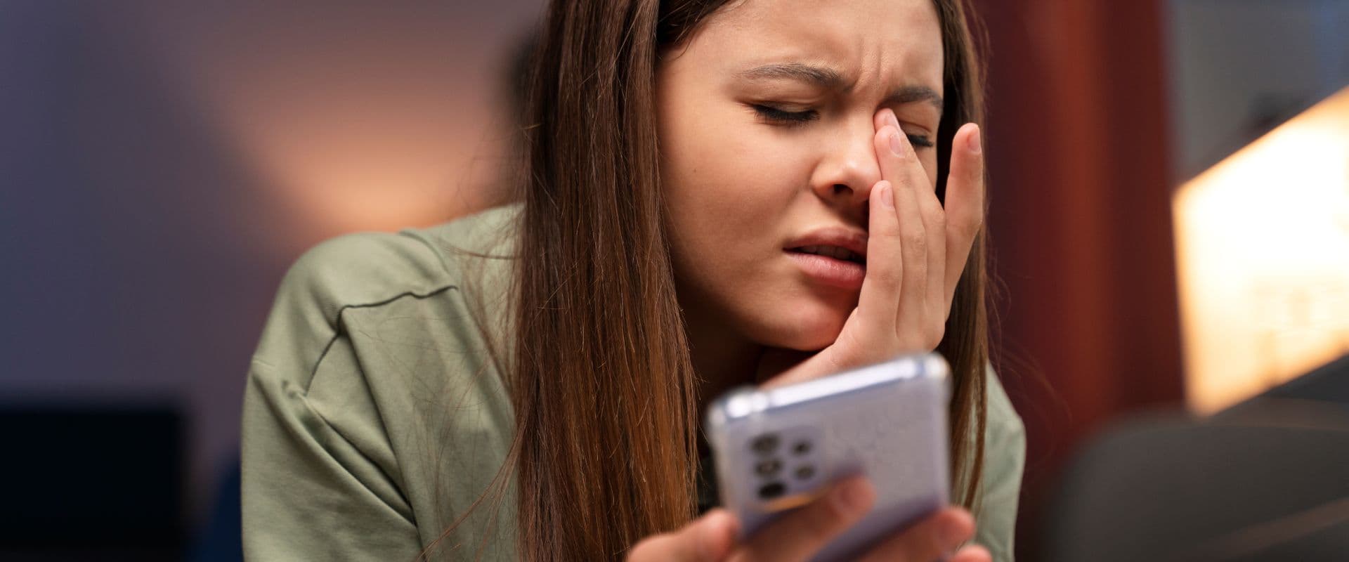 Mulher com expressão de desgosto ao olhar para smartphone, indicando frustração ou decepção.