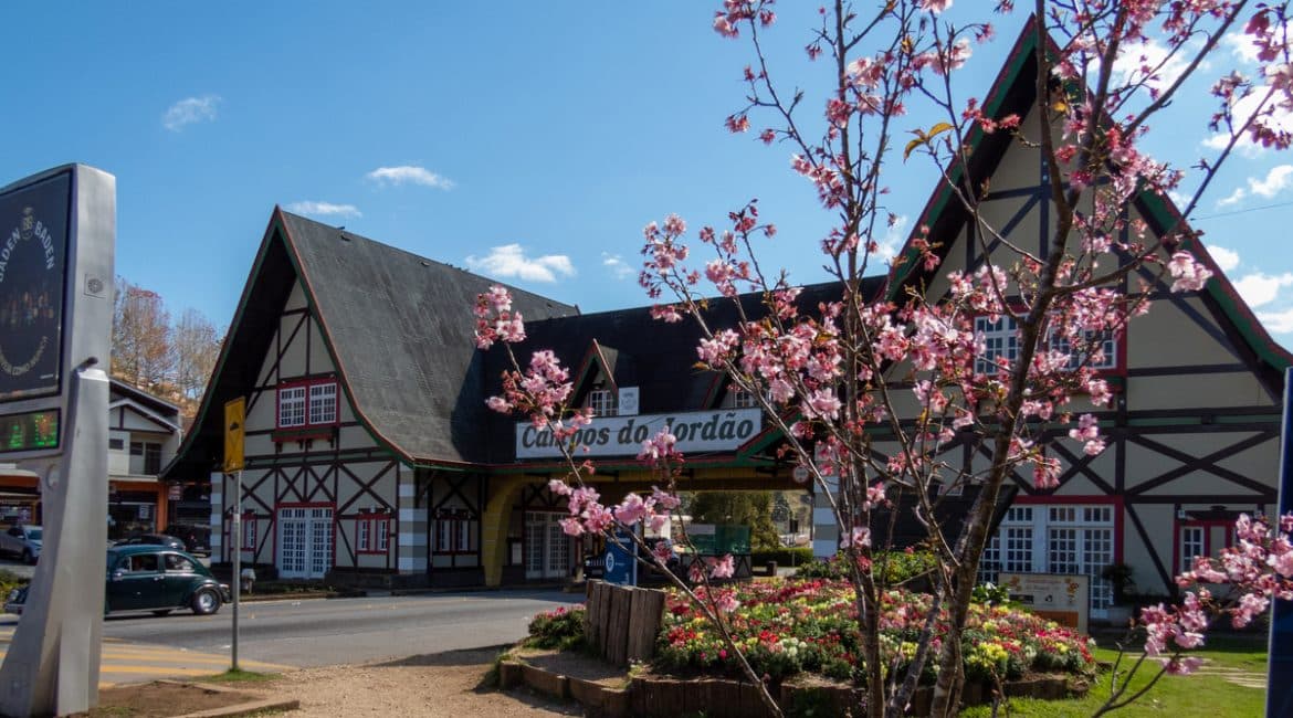 Imagem da arquitetura típica de Campos do Jordão, com flores ao fundo. Destaca-se o clima europeu da cidade e suas belezas naturais.