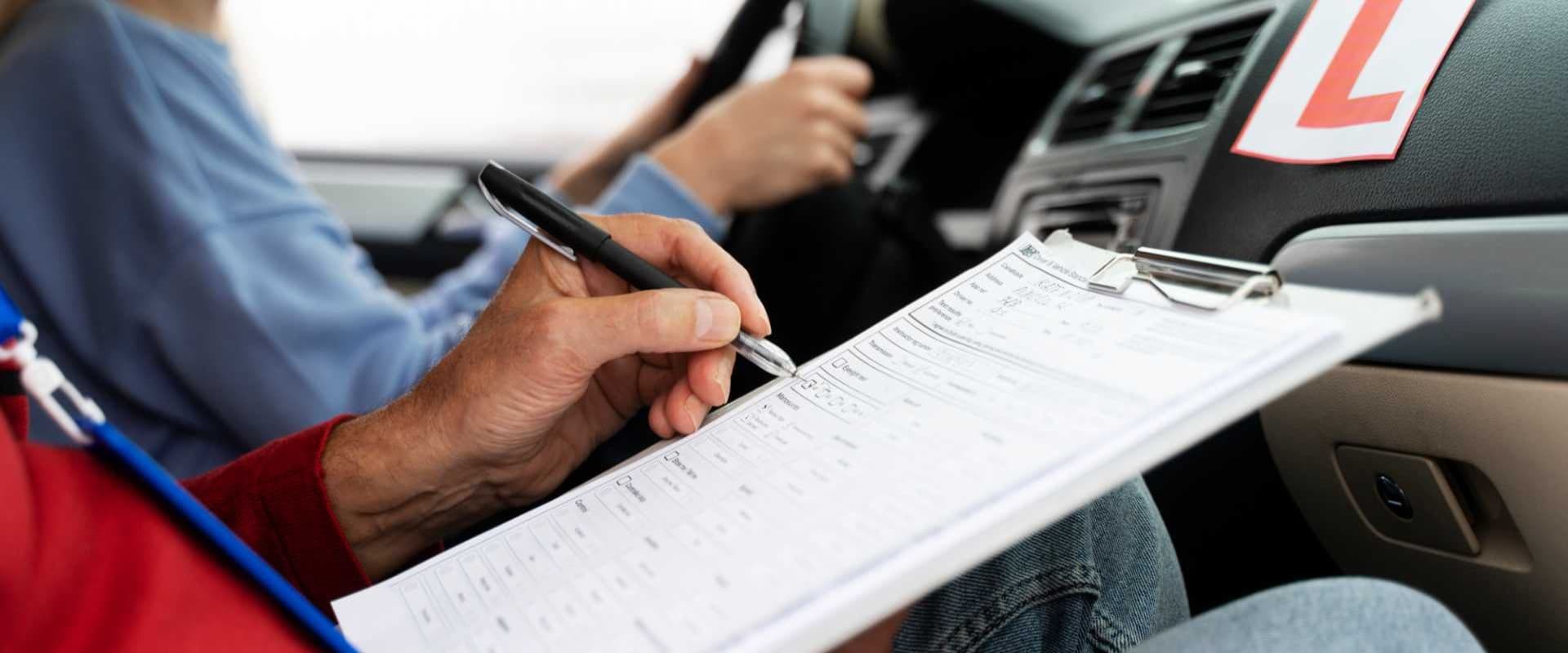Pessoa realizando prova de direção em um carro, supervisionada por instrutor com placa 'L' no painel, na busca pela habilitação. Ambiente externo ensolarado.