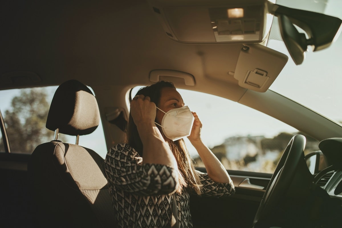 Mulher motorista coloca a mascara; ela está ao volante, com uma blusa de estampas - 7 dicas para ser um bom motorista de aplicativo