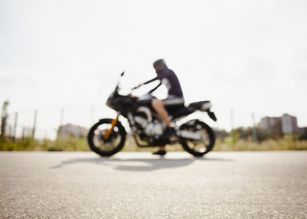 Foto borrada de um motociclista em cima de uma moto.