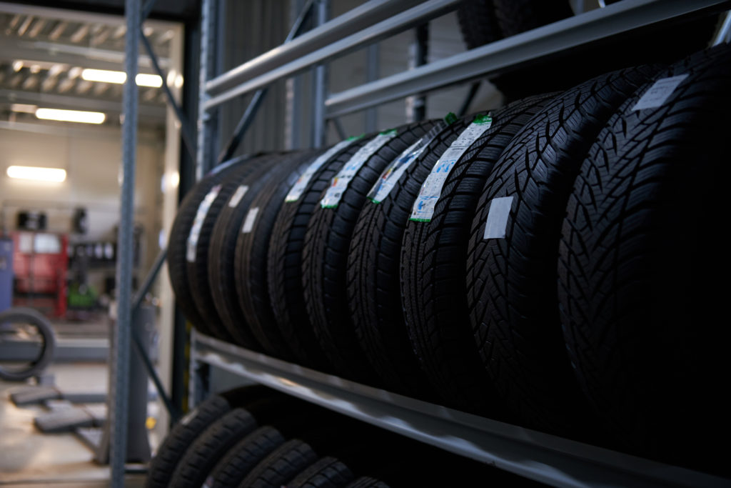 Na imagem há uma prateleira com vários pneus novos. Os pneus carecas devem ser trocados para evitar aquaplanagem.