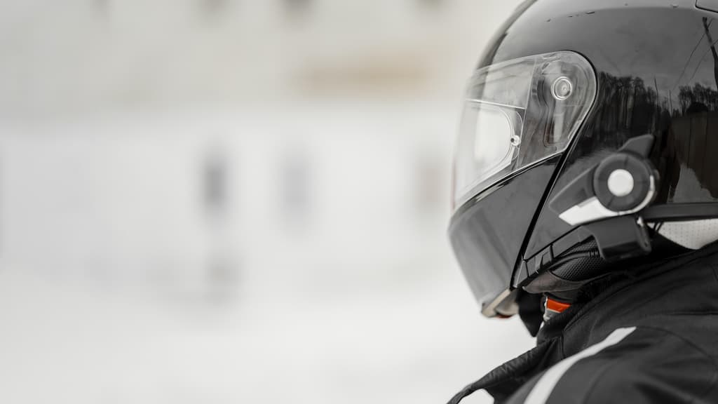 Na imagem há um motociclista usando um dos tipos de capacete, com o fundo desfocado