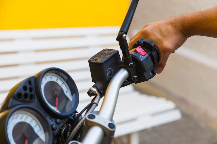 Na imagem há uma pessoa segurando o guidão de uma motocicleta.